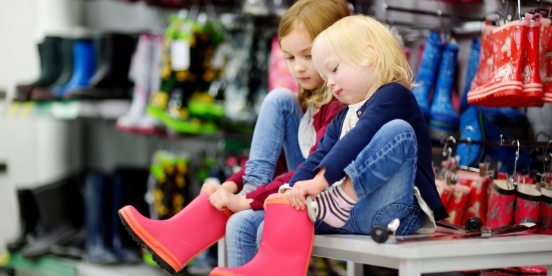 Mdchen probieren im Geschft Gummistiefel an