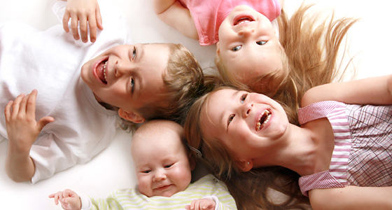 Vier Babys bzw. Kinder liegen im Kreis